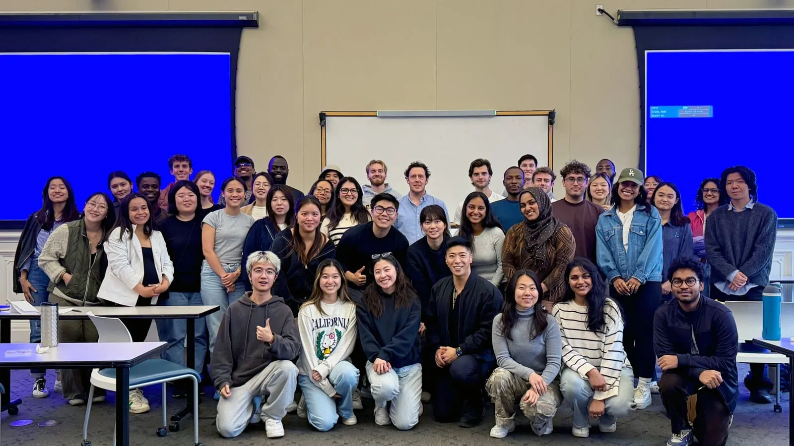 A large cohort of graduate students posed together at the front of a Berkeley lecture hall after a prototyping session